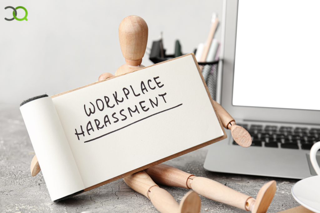 mannequin holding workplace harassment placard with laptop background